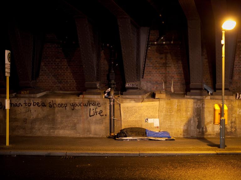 Ein Obdachloser schläft unter einer Brücke in Berlin.