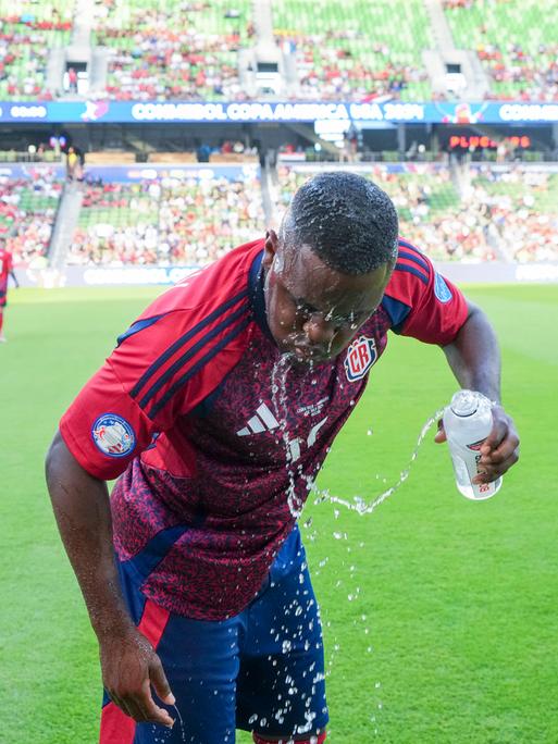 Ein Fußballspieler schüttet sich Wasser über den Kopf.