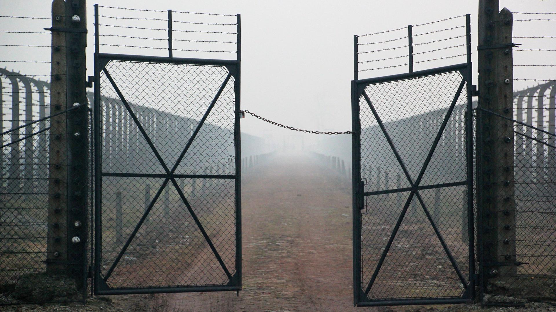 Stacheldraht und Gittertür mit Blick von der Lagerstraße in Richtung Kommandaturgebäude im Bauabschnitt B II des Vernichtungslagers Auschwitz-Birkenau, aufgenommen am 10.12.2014. 