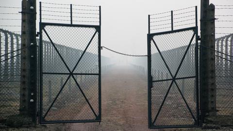 Stacheldraht und Gittertür mit Blick von der Lagerstraße in Richtung Kommandaturgebäude im Bauabschnitt B II des Vernichtungslagers Auschwitz-Birkenau, aufgenommen am 10.12.2014. 