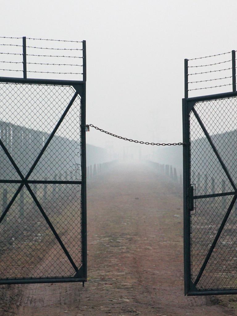 Stacheldraht und Gittertür mit Blick von der Lagerstraße in Richtung Kommandaturgebäude im Bauabschnitt B II des Vernichtungslagers Auschwitz-Birkenau, aufgenommen am 10.12.2014. 