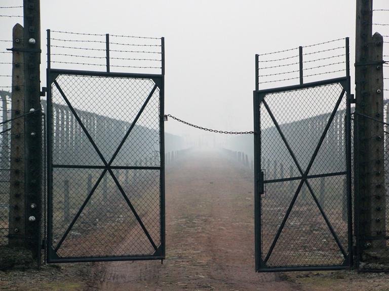 Stacheldraht und Gittertür mit Blick von der Lagerstraße in Richtung Kommandaturgebäude im Bauabschnitt B II des Vernichtungslagers Auschwitz-Birkenau, aufgenommen am 10.12.2014. 