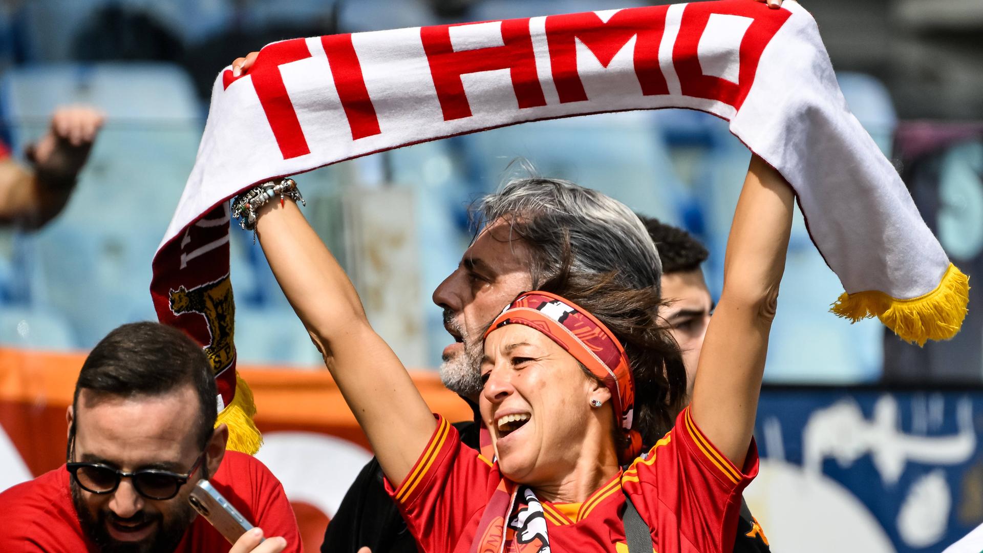 Eine Frau hält einen Schal in die Höhe, auf dem "Ti amo" steht, was auf Italienisch "Ich liebe Dich" bedeutet. Sie schaut glücklich. Eine Frau hält einen Schal in die Höhe, auf dem "Ti amo" steht, was auf Italienisch "Ich liebe Dich" bedeutet. Sie schaut glücklich.