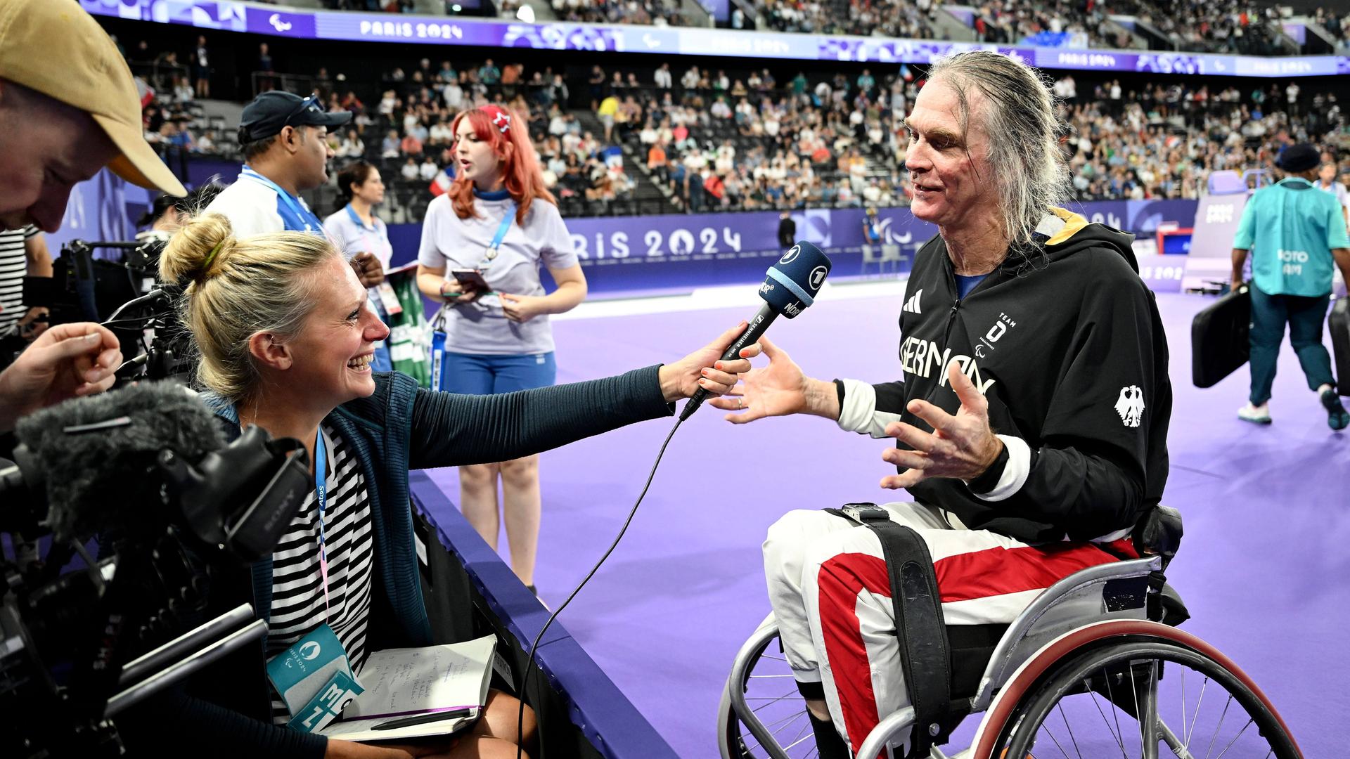 Thomas Wandschneider sitzt in seinem Rollstuhl vor einem Mikrofon beim Interview nach seinem 3.Platz im Badminton bei den Paralympics 2024 in Paris. 