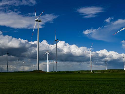 Dunkle Regenwolken ziehen über die Landschaft mit einem Windenergiepark im Landkreis Oder-Spree