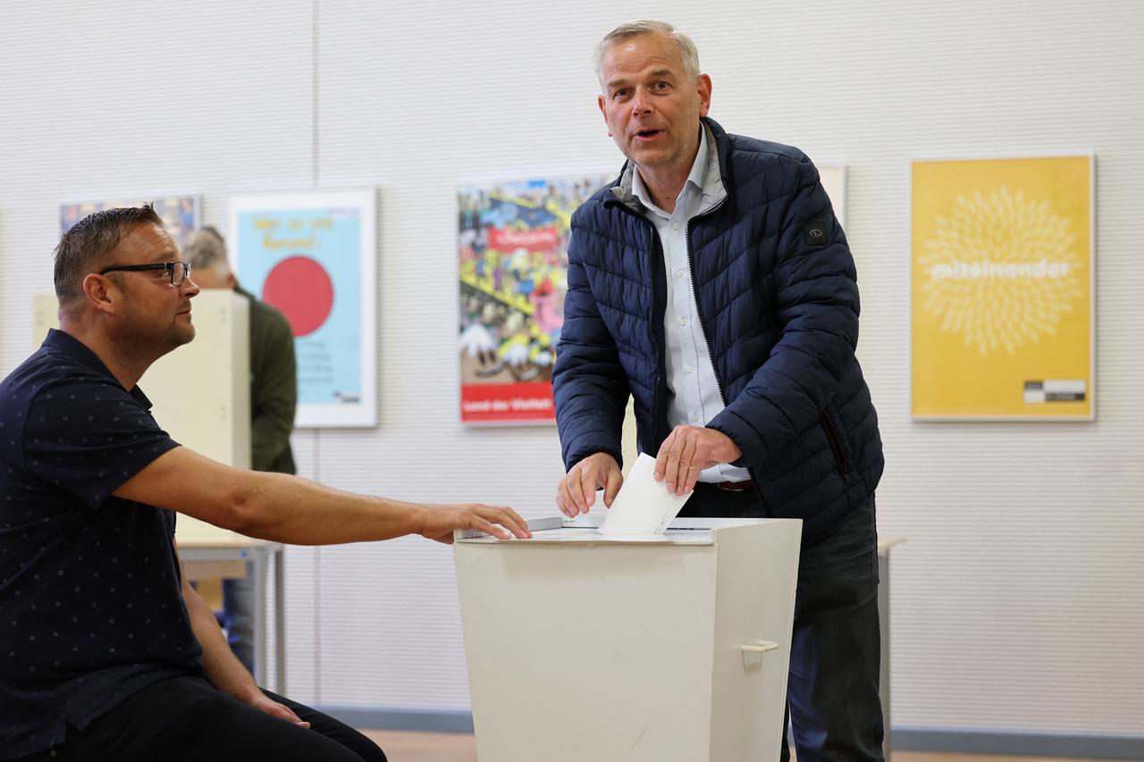 Ein Mann mit grauen Haaren wirft seinen Stimmzettel in eine Wahlurne.