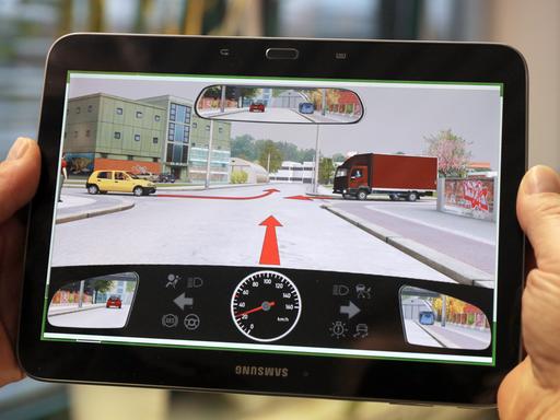 Bei einer theoretischen Führerscheinprüfung zeigt der Prüfer ein Tablet mit einer Prüfungsfrage.