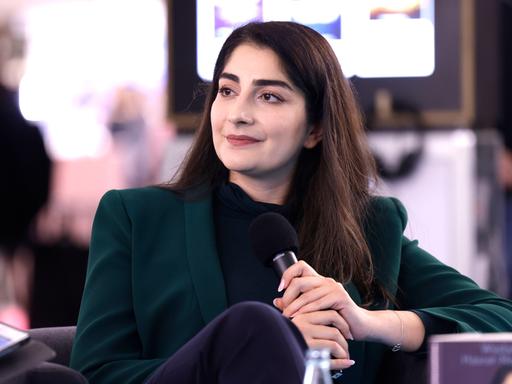 Waslat Hasrat-Nazimi sitzt bei einem Gespräch auf der Frankfurter Buchmesse 2022 mit einem Mikrofon in der Hand in einem Sessel.