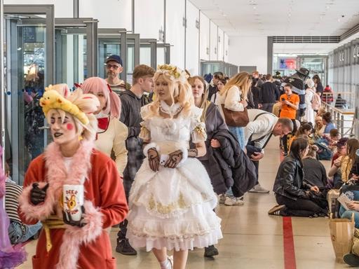 Ein Messegang mit vielen Menschen, manche von Ihnen sind verkleidet.