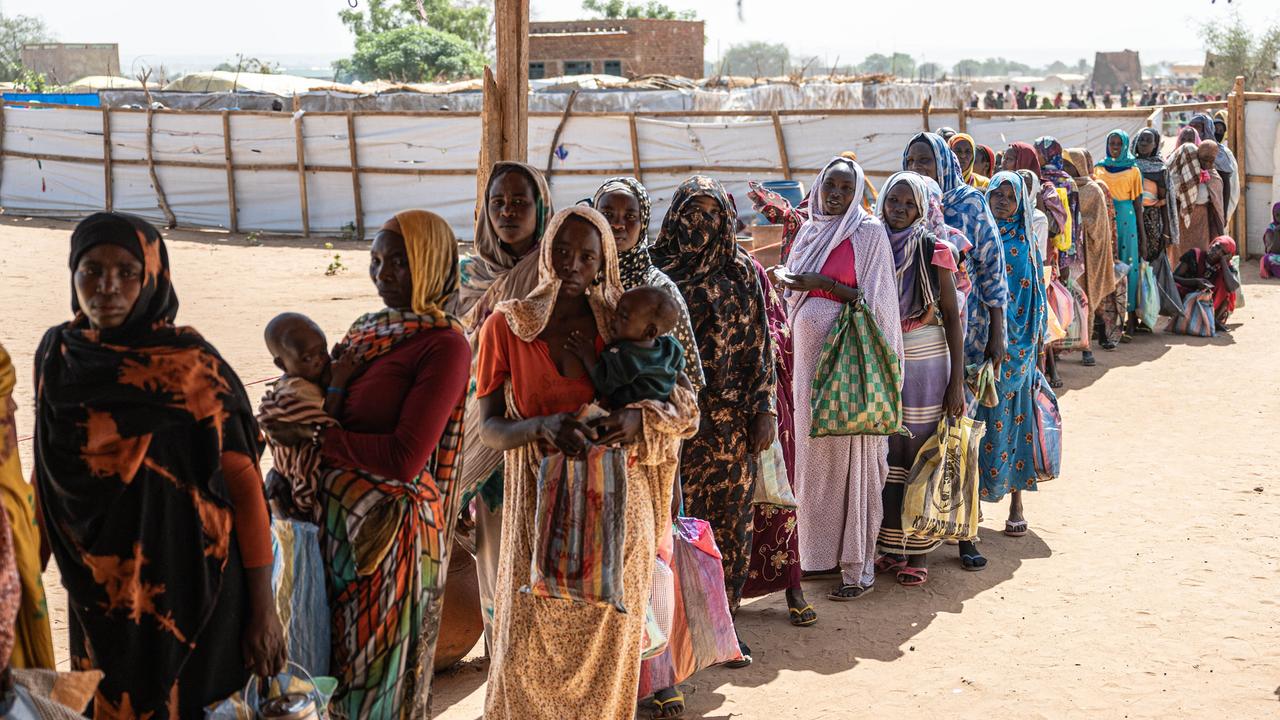 Sudanesische Fraeun und Kinder warten in einer Registrierungsstelle in Adre, Tschad, in einer Schlange auf die Verteilung von Hilfsgütern 