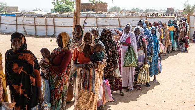 Sudanesische Fraeun und Kinder warten in einer Registrierungsstelle in Adre, Tschad, in einer Schlange auf die Verteilung von Hilfsgütern 