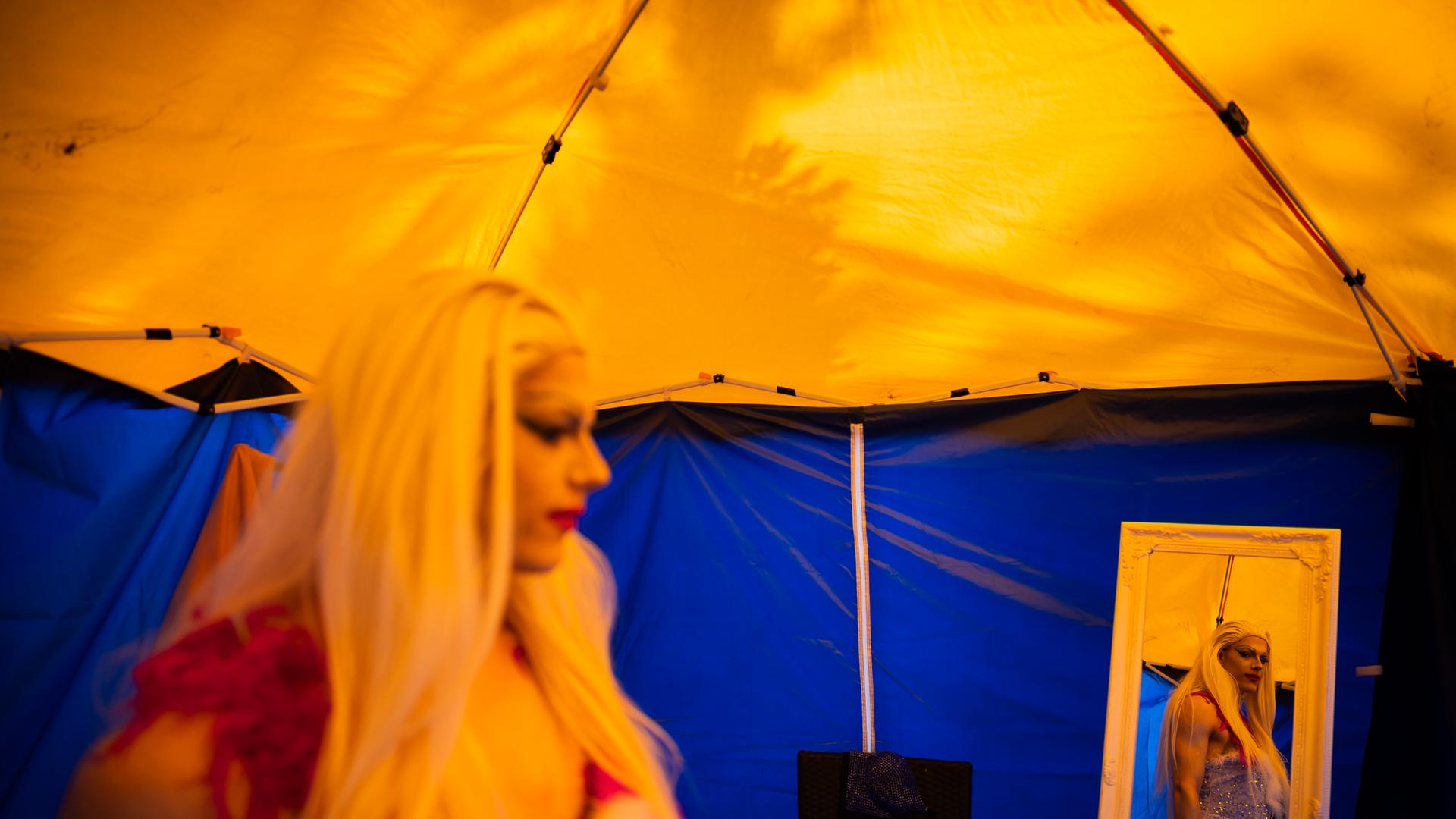 Dragqueen Janoma Bange steht beim Demokratiefest in Bad Freienwalde in einem Zelt. Sie ist in einem Spiegel zu sehen. 