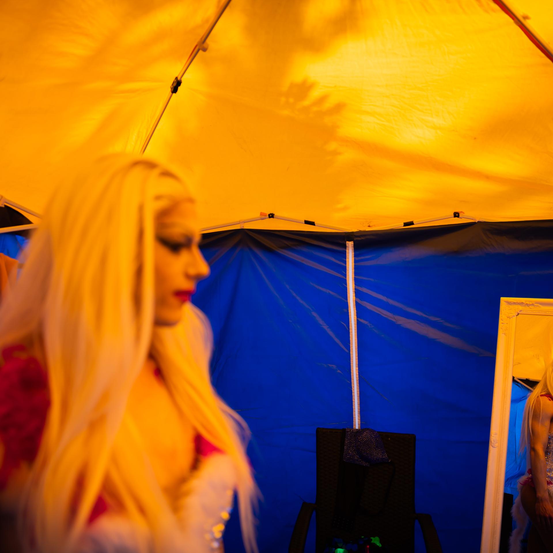 Dragqueen Janoma Bange steht beim Demokratiefest in Bad Freienwalde in einem Zelt. Sie ist in einem Spiegel zu sehen. 