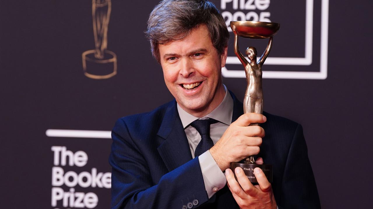 Das Foto zeigt den Autor David Szalay, der die Trophäe des Booker Prize in der Hand hält.