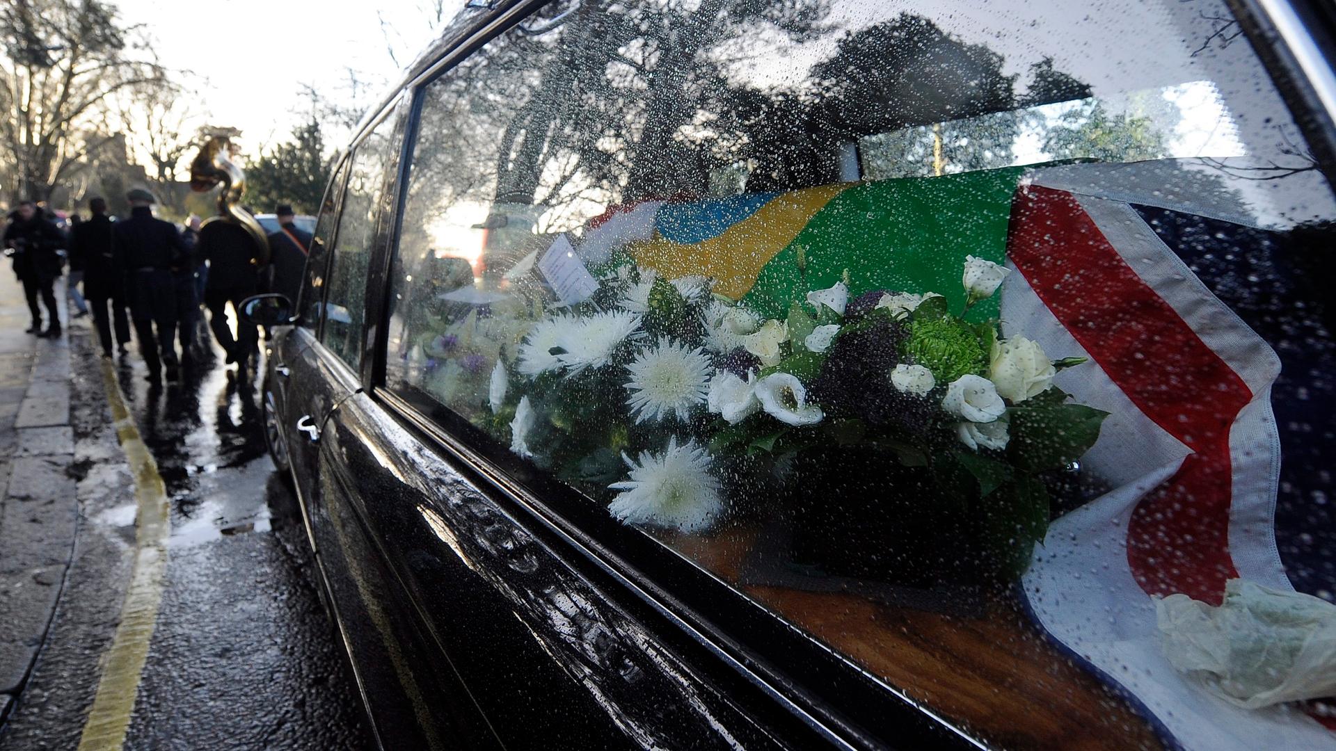 Leichenwagen mit dem Sarg von Ronnie Biggs, eingehüllt in die britische und die brasilianische Flagge und einer Brass Band, die ihm zu Ehren spielt.