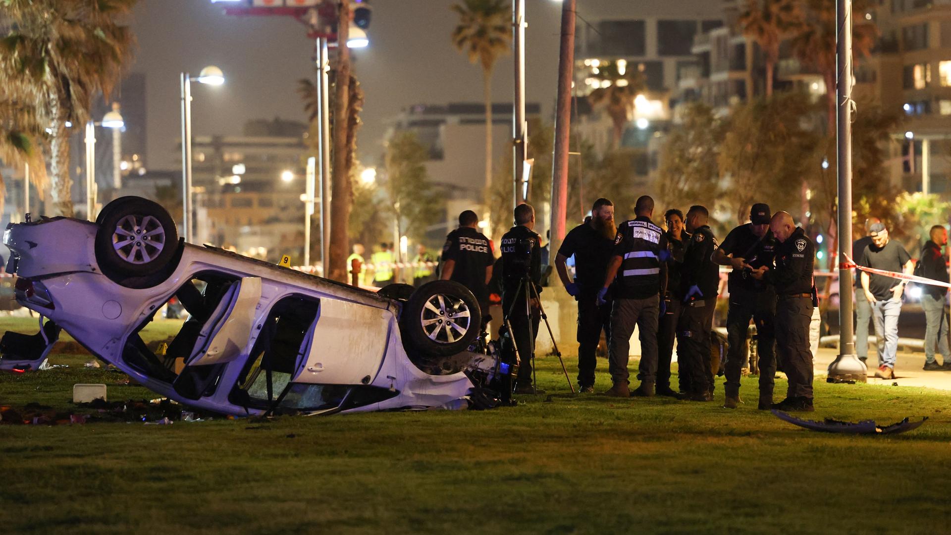 Einsatzkräfte am Anschlagsort in Tel Aviv. Das Auto des Attentäters liegt auf dem Dach.