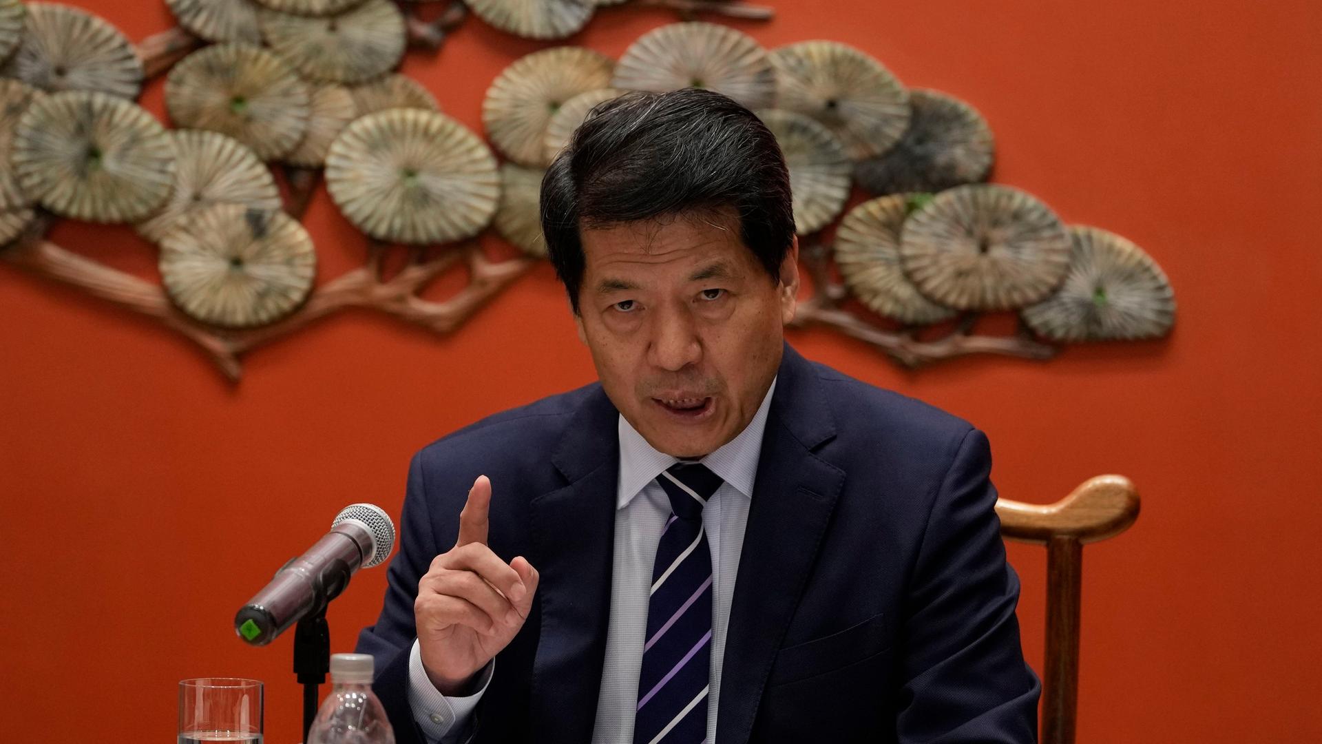 Der chinesische Sonderbeauftragte Li Hui spricht auf einer Pressekonferenz. Hinter ihm ein Muschelornament an einer roten Wand.