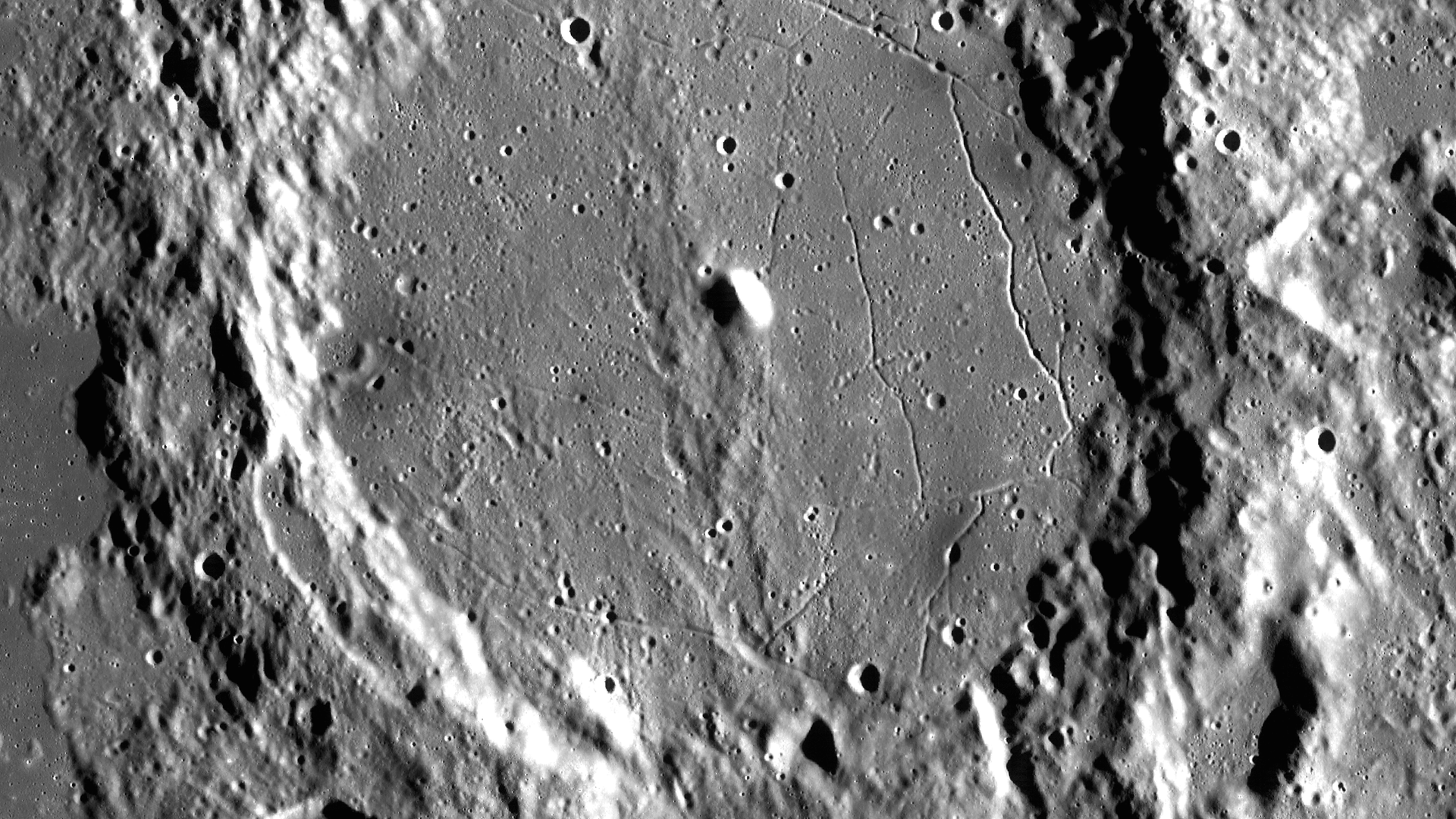 Eine Schwarz-Weiß-Aufnahme zeigt einen Krater mit einer Wölbung in der Mitte. Eine Schwarz-Weiß-Aufnahme zeigt einen Krater mit einer Wölbung in der Mitte.