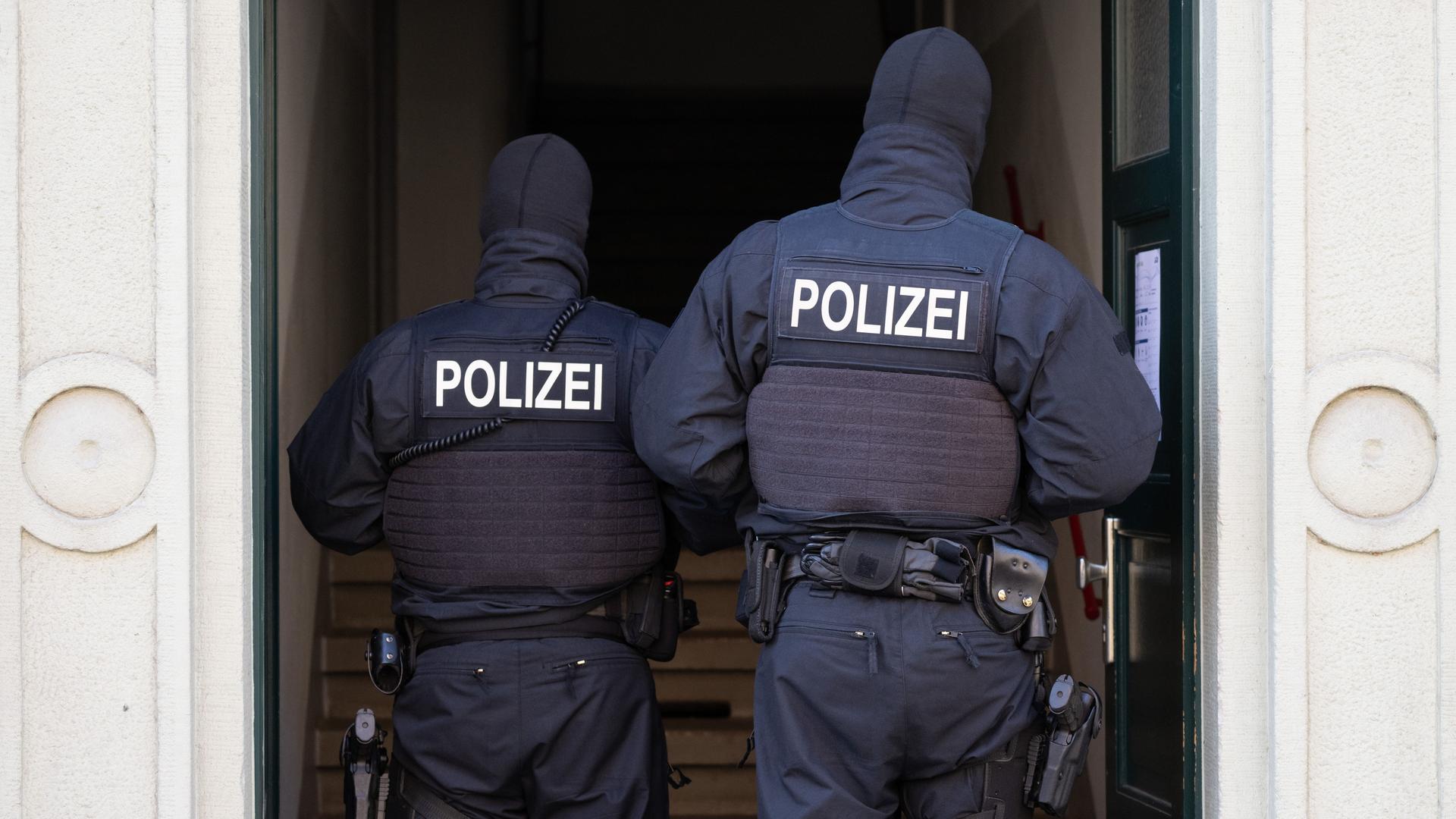 Polizisten stehen während einer Razzia gegen mutmaßliche Rechtsextreme in einem Hauseingang im Dresdner Stadtteil Cotta. Polizisten stehen während einer Razzia gegen mutmaßliche Rechtsextreme in einem Hauseingang im Dresdner Stadtteil Cotta.