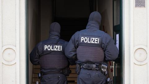 Polizisten stehen während einer Razzia gegen mutmaßliche Rechtsextreme in einem Hauseingang im Dresdner Stadtteil Cotta. 