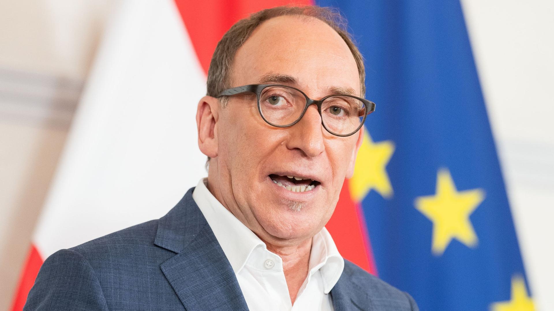 Österreichs Gesundheitsminister Johannes Rauch während gestikuliert, während er vor einem Mikrofon steht.