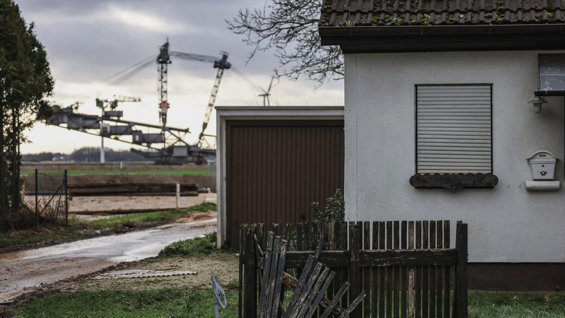 Ein Braunkohlebagger steht im Ortsteil Keyenberg hinter einem verlassenen Haus. Noch schaufeln die Braunkohlebagger im Rheinischen Revier weiter.