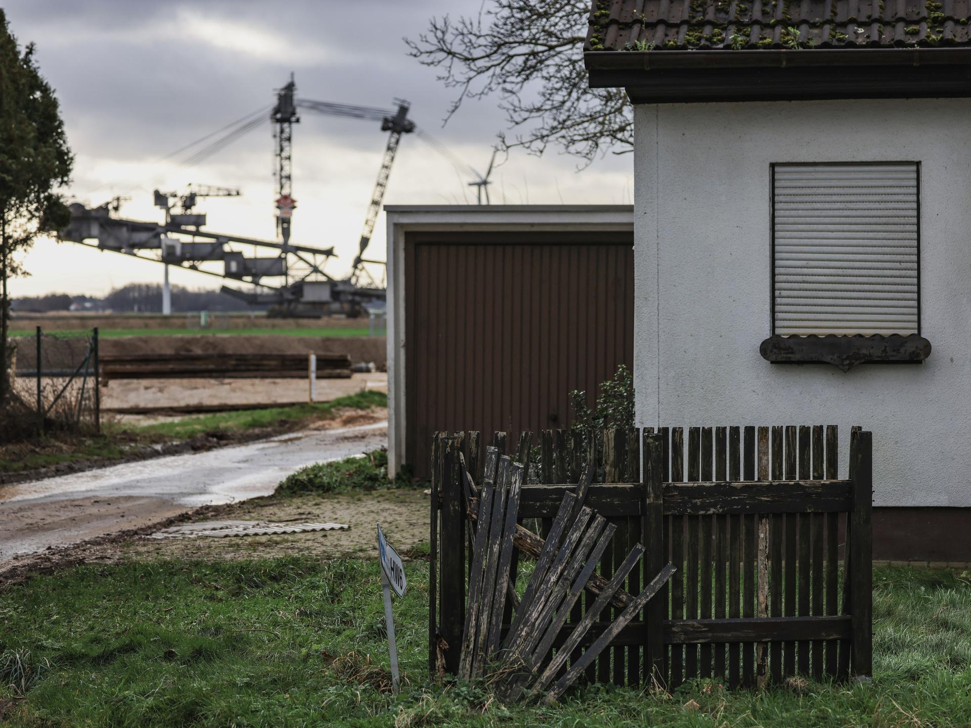 Ein Braunkohlebagger steht im Ortsteil Keyenberg hinter einem verlassenen Haus. Noch schaufeln die Braunkohlebagger im Rheinischen Revier weiter.