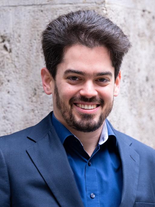 Lahav Shani, der zukünftige Chefdirigent der Münchner Philharmoniker, posiert bei seiner Vorstellung in einem blauen Sakko für Pressefotos.