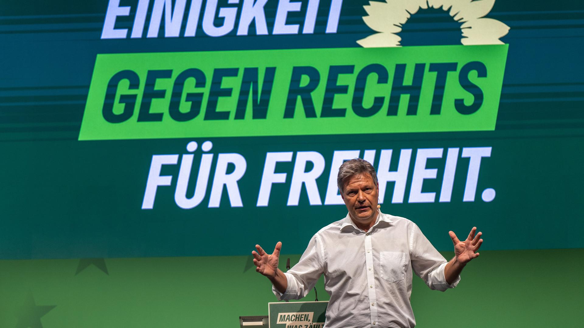 Robert Habeck, Bundesminister für Wirtschaft und Klimaschutz, spricht beim kleinen Parteitag von Bündnis 90/Die Grünen in Potsdam. Er trägt ein weißes Hemd und gestikuliert energisch. Hinter ihm sieht man an der Wand den Slogan "Einigkeit gegen rechts. Für Freiheit".