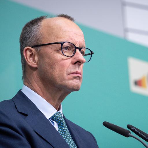 Friedrich Merz steht bei einer Pressekonferenz im Konrad-Adenauer-Haus mit ernstem Blick am Mikrofon vor einem türkisen Hintergrund mit dem Logo der CDU.