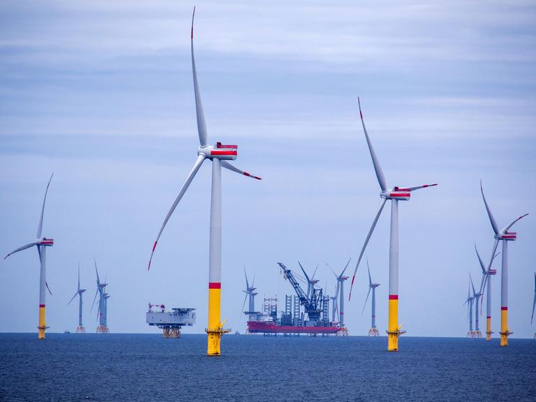 Ein Arbeitsschiff steht auf Stelzen zwischen Windrädern, die in der Ostsee zwischen den Inseln Rügen und Bornholm (Dänemark) errichtet wurden. 