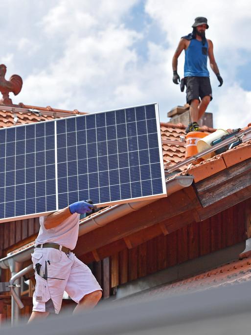 Solarmodule werden auf ein Hausdach transportiert.