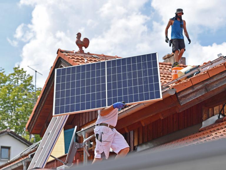 Solarmodule werden auf ein Hausdach transportiert.