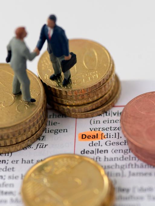 Figuren stehen auf einem Stapel Münzen und geben sich die Hand.