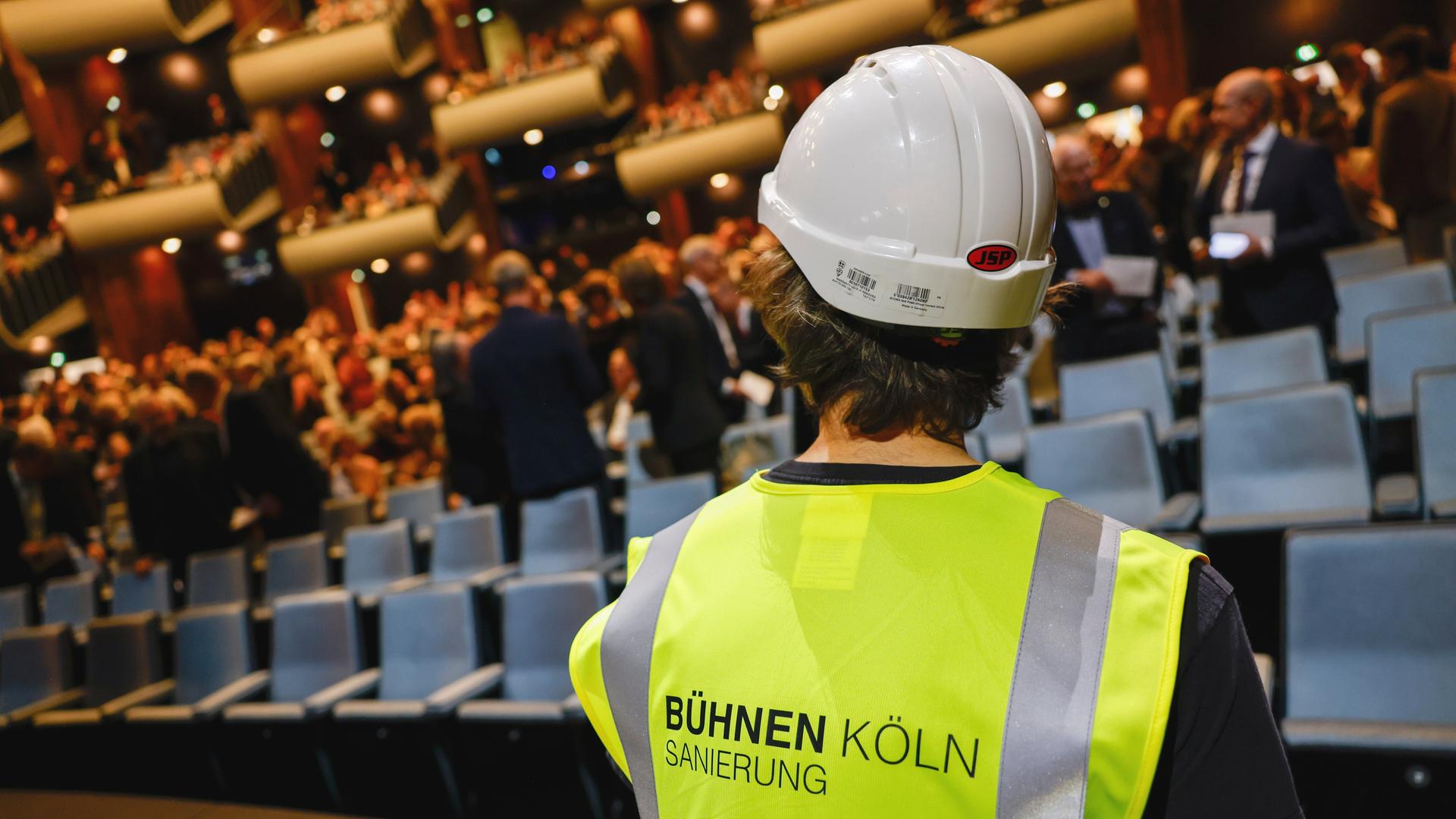 Ein als Bauarbeiter verkleideter Schauspieler sitzt auf der Bühne. Oper und Schauspiel Köln feiern den Wiedereinzug in ihre angestammten Häuser am Offenbachplatz mit einer großen, festlichen Gala. Die Sanierung der Kölner Bühnen hat 14 Jahre gedauert. Ein als Bauarbeiter verkleideter Schauspieler sitzt auf der Bühne. Oper und Schauspiel Köln feiern den Wiedereinzug in ihre angestammten Häuser am Offenbachplatz mit einer großen, festlichen Gala. Die Sanierung der Kölner Bühnen hat 14 Jahre gedauert.
