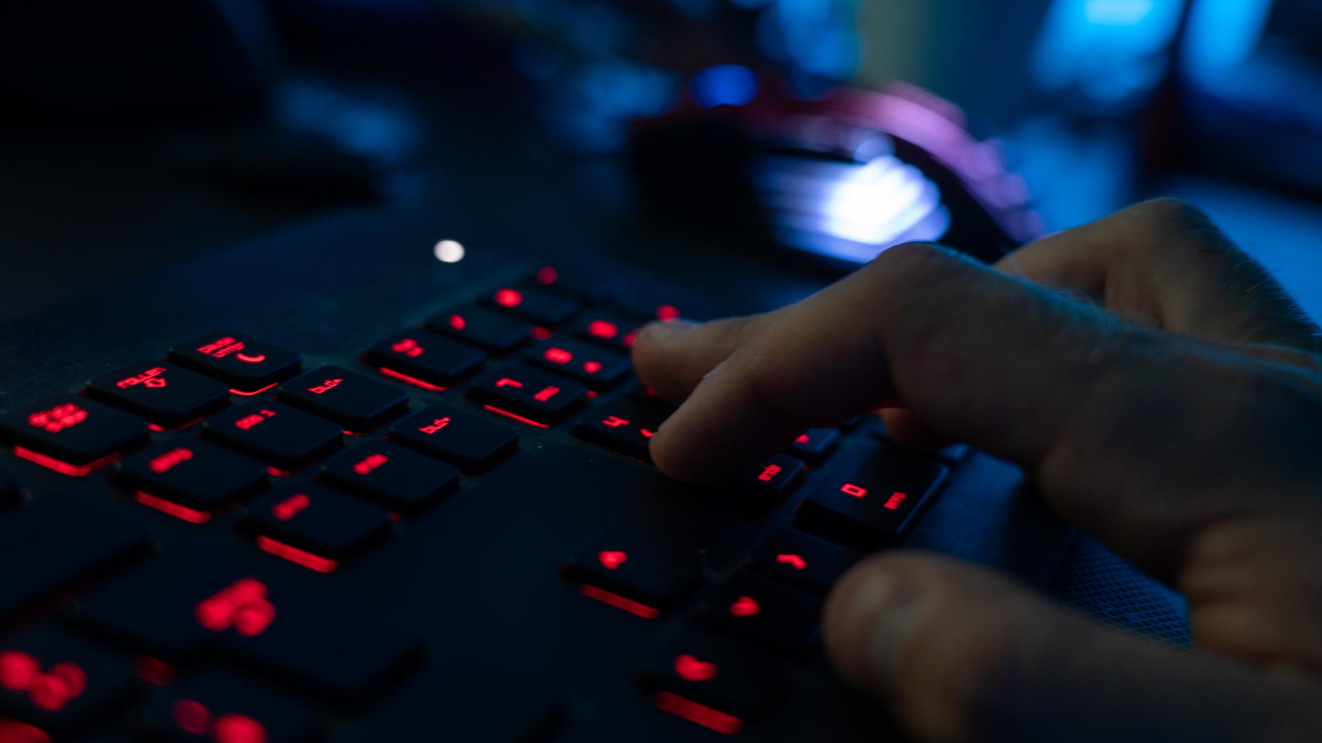 Eine Hand tippt am Rechner auf einer erleuchteten Tastatur. Eine Hand tippt am Rechner auf einer erleuchteten Tastatur.