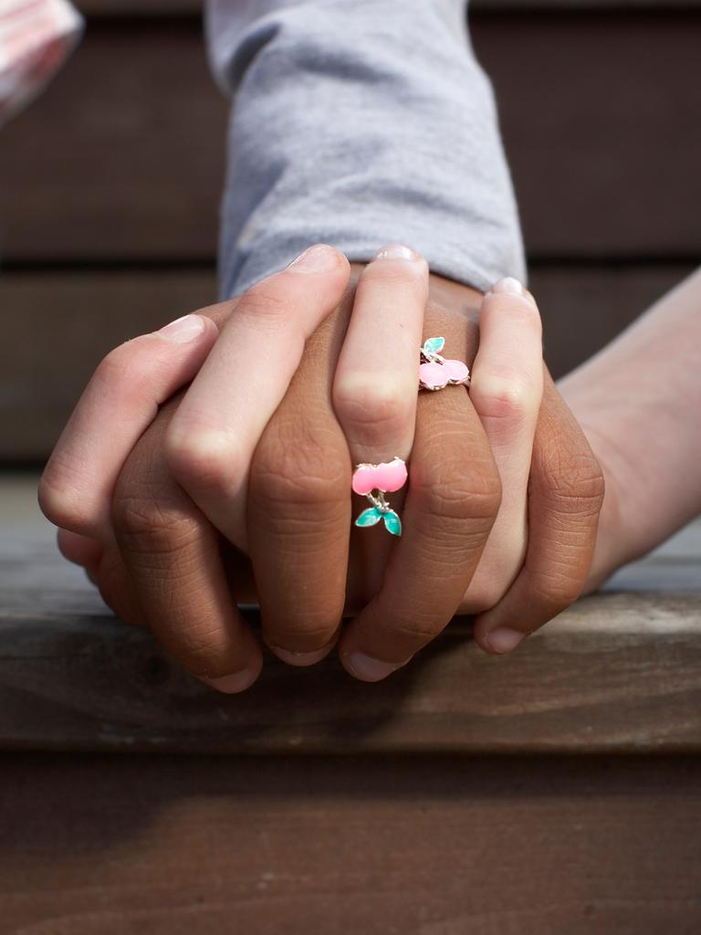 Freundschaftsringe in Kirschform an zwei eng umschlungenen Händen.