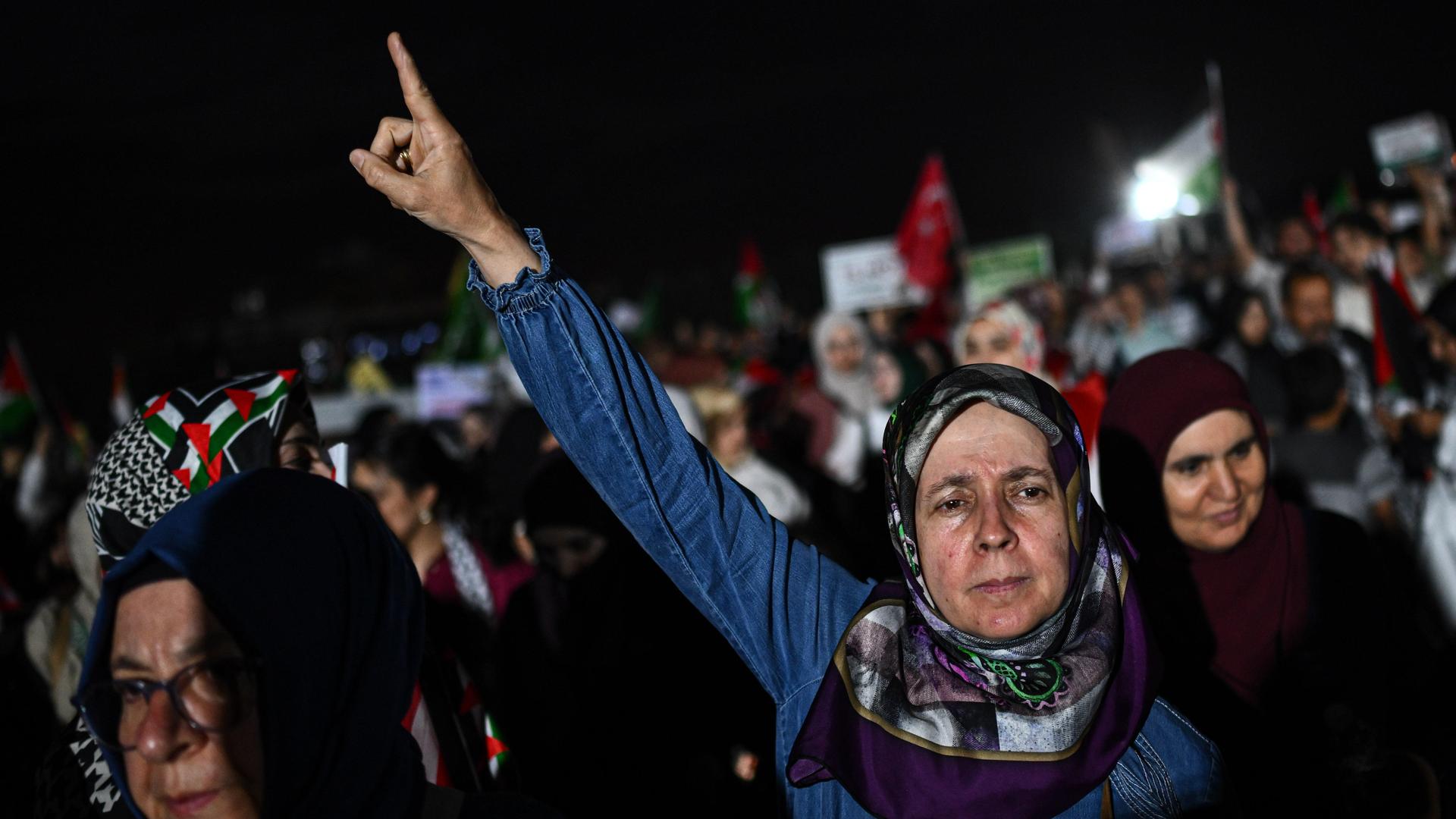 Eine Demonstration von Unterstützer*innen des "Global March to Gaza" laufen durch Kairo. Im Vordergrund ist eine ältere Frau mit Kopf zu sehen, die ihren rechten Arm kämpferisch in die Luft streckt. Eine Demonstration von Unterstützer*innen des "Global March to Gaza" laufen durch Kairo. Im Vordergrund ist eine ältere Frau mit Kopf zu sehen, die ihren rechten Arm kämpferisch in die Luft streckt.