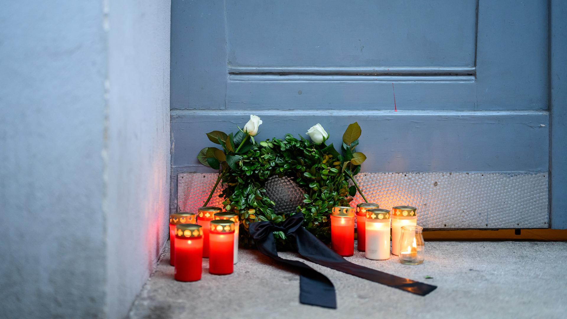 Bei einer von mehreren politischen Parteien organisierten Mahnwache für Opfer von Femiziden stehen Trauerlichter und ein kleiner Kranz vor einer Tür