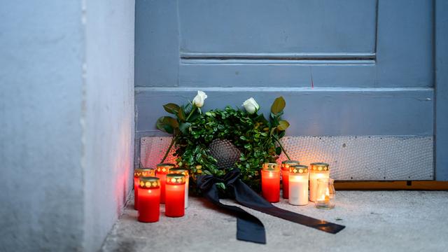 Bei einer von mehreren politischen Parteien organisierten Mahnwache für Opfer von Femiziden stehen Trauerlichter und ein kleiner Kranz vor einer Tür