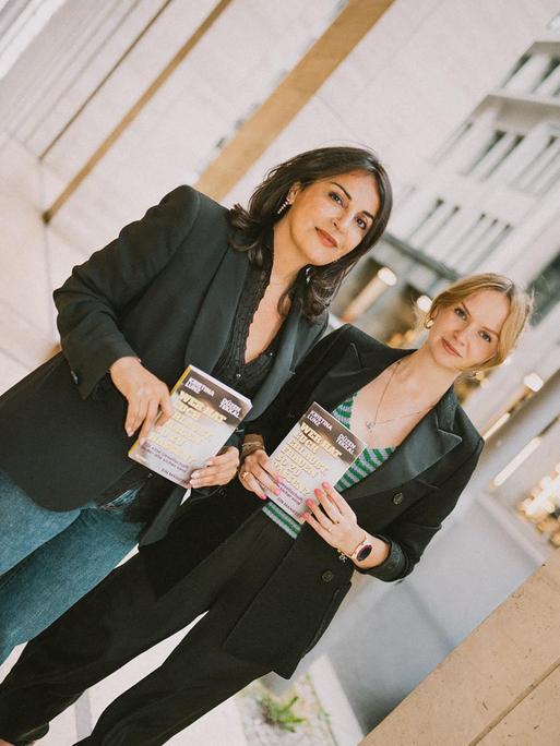 Düzen Tekkal und Kristina Lunz halten beide das Buch "Wer hat euch erlaubt, Frauen zu hassen" vor ihrem Körper Richtung Kamera.