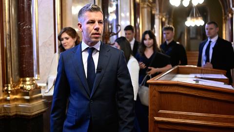Peter Magyar geht durch das Parlamentsgebäude in Budapest. Er trägt einen schwarzen Anzug mit schwarzer Krawatte.