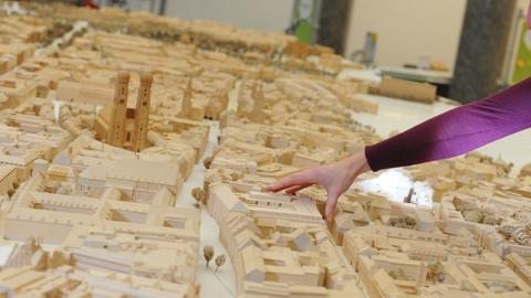 Eine Modellbauerin setzt ein Gebäude in ein hölzernes Modell der Münchener Altstadt ein.