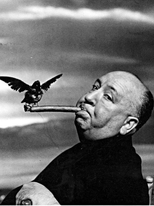 Alfred Hitchcock blickt lakonisch in die Kamera. Er raucht eine Zigarre, auf der ein furchterregender Vogel sitzt.