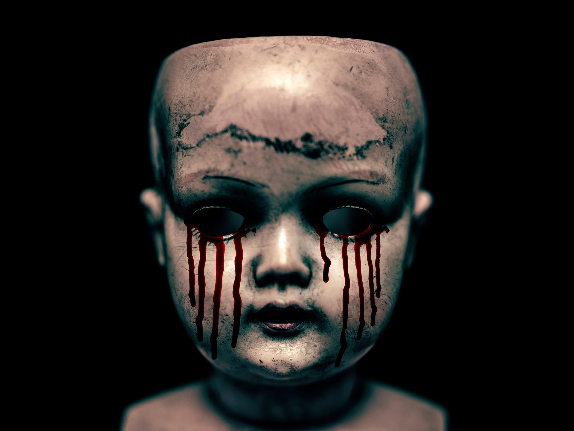 Ein gruseliger Puppenkopf mit blutenden Augen vor schwarzem Hintergrund