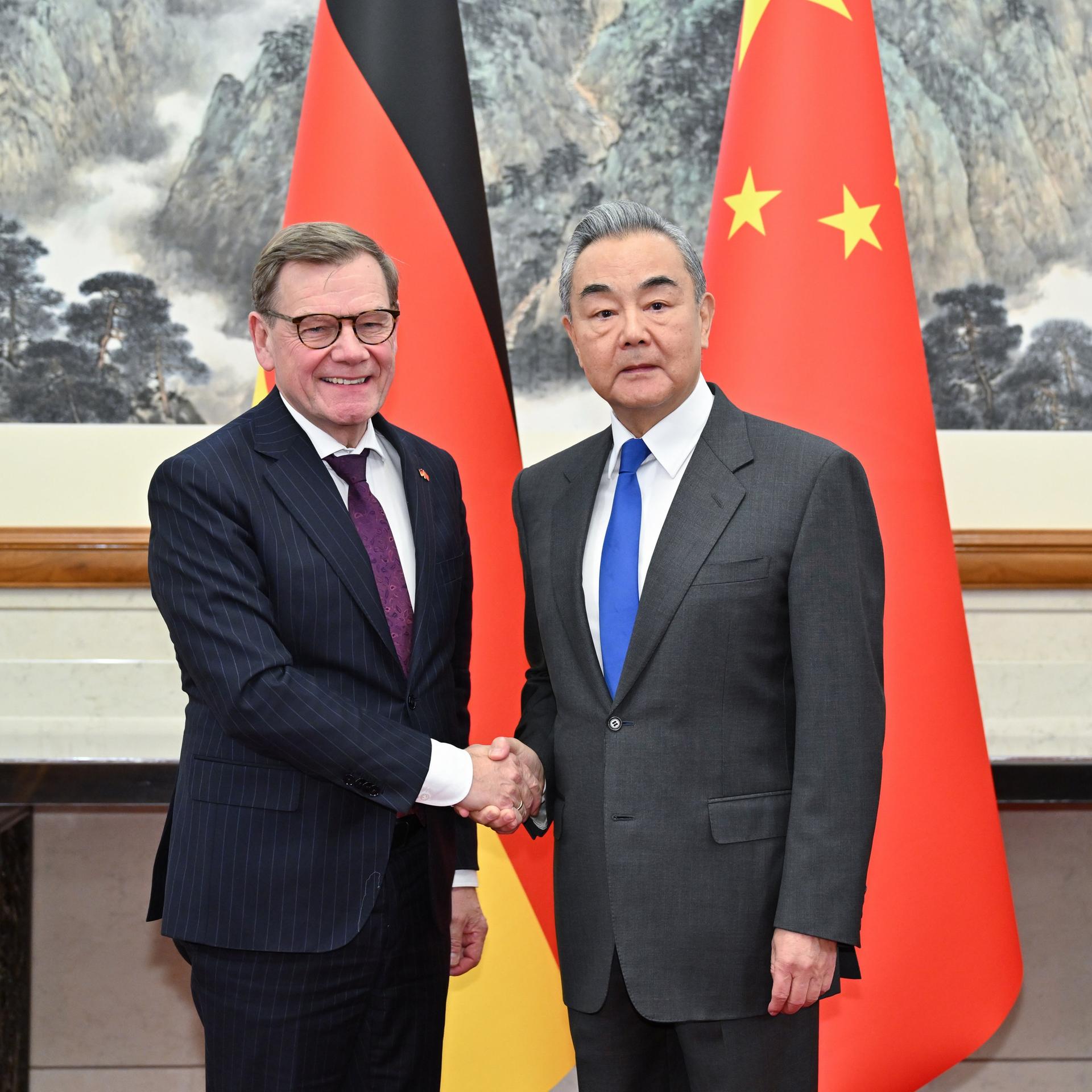 Bundesaußenminister Wadephul und sein chinesischer Amtskollege Wang stehen vor den Nationalflaggen beider Länder und geben sich die Hand.