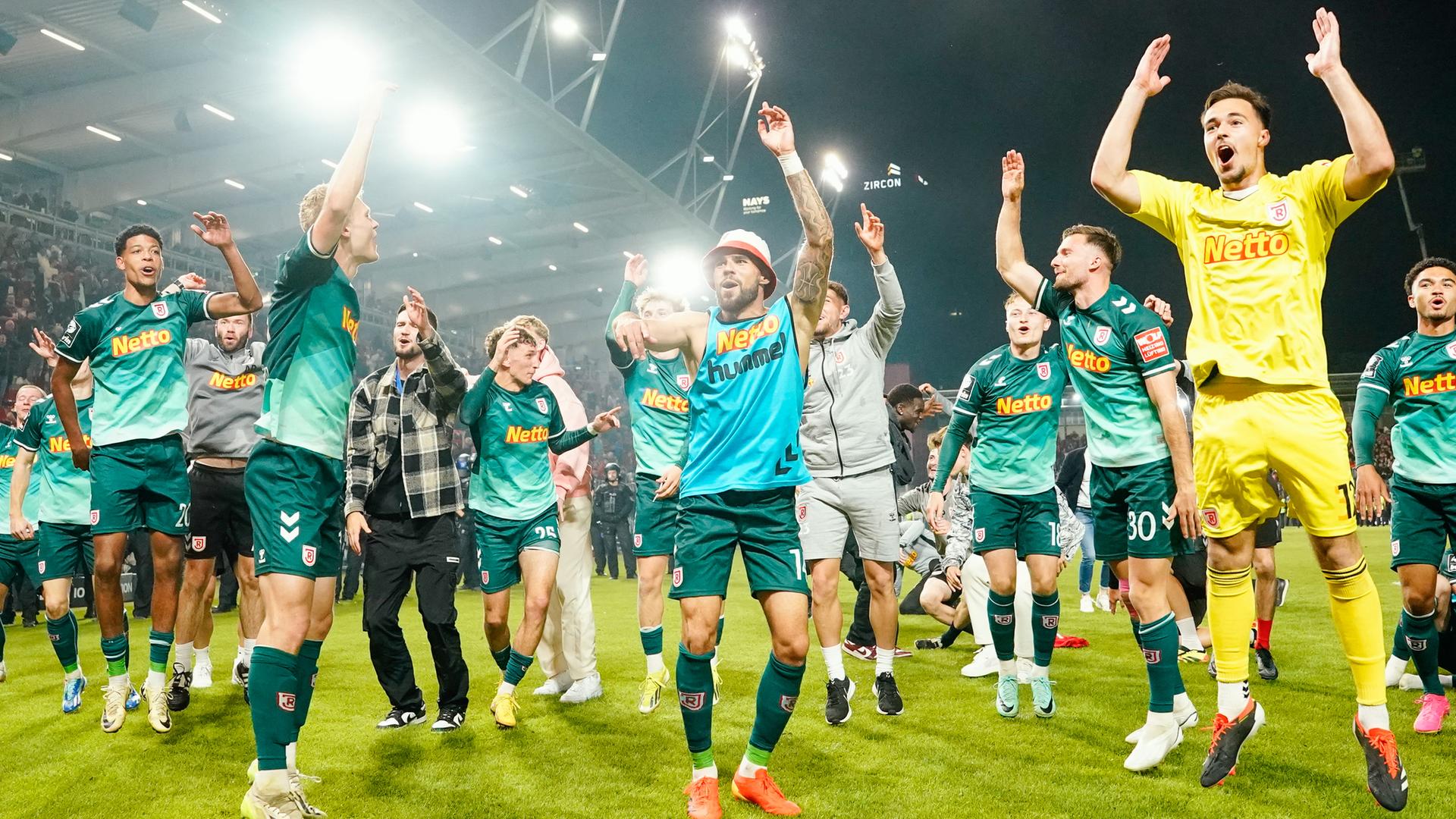 Mehrere Fußballspieler springen hoch und reißen dabei zum Jubel ihre Arme in die Höhe. Mehrere Fußballspieler springen hoch und reißen dabei zum Jubel ihre Arme in die Höhe.