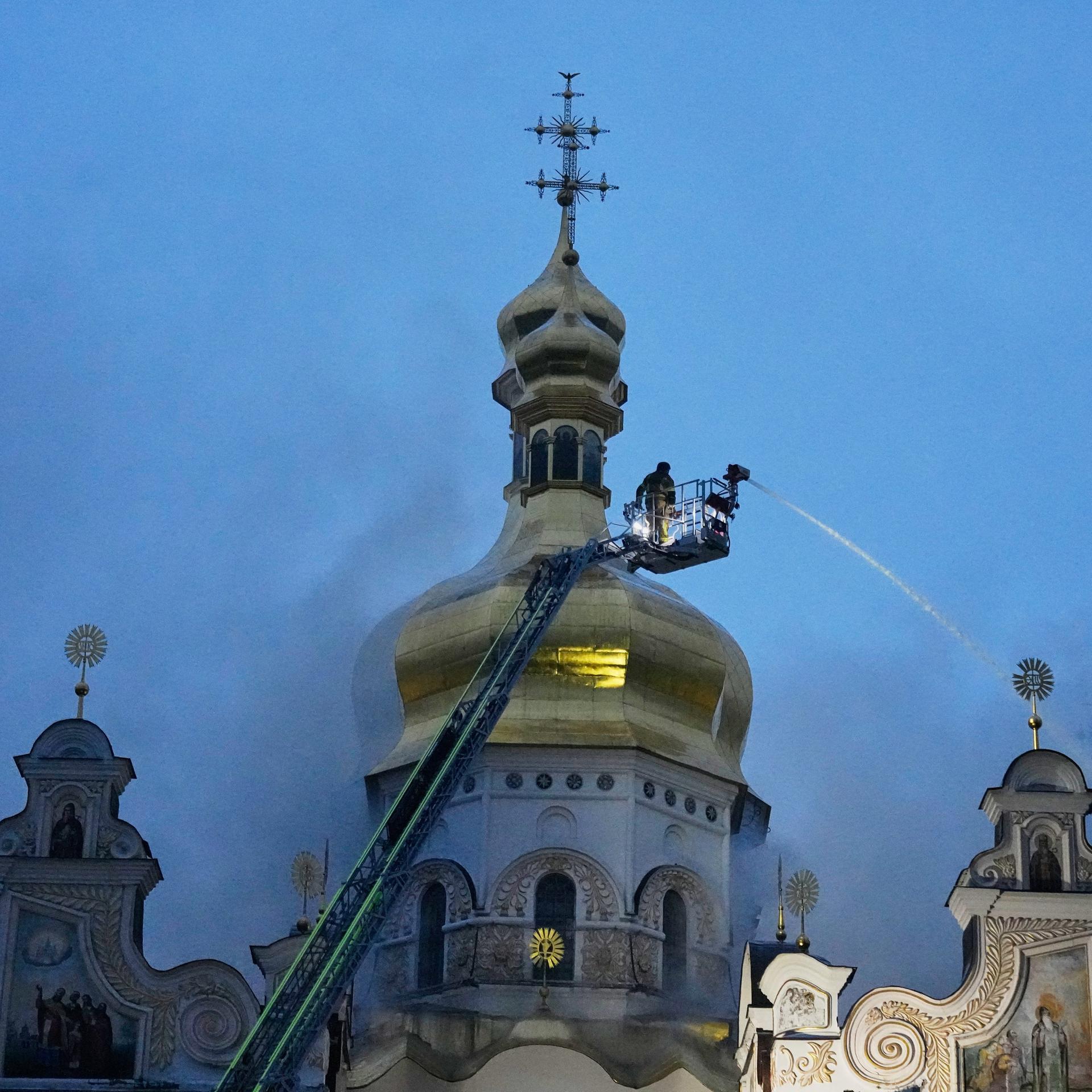 Ukraine, Kiew: Feuerwehrleute löschen einen Brand in der Kiewer Mariä-Entschlafenskirche Pechersk-Lawra, auch bekannt als Höhlenkloster, nach einem russischen Raketen- und Drohnenangriff.