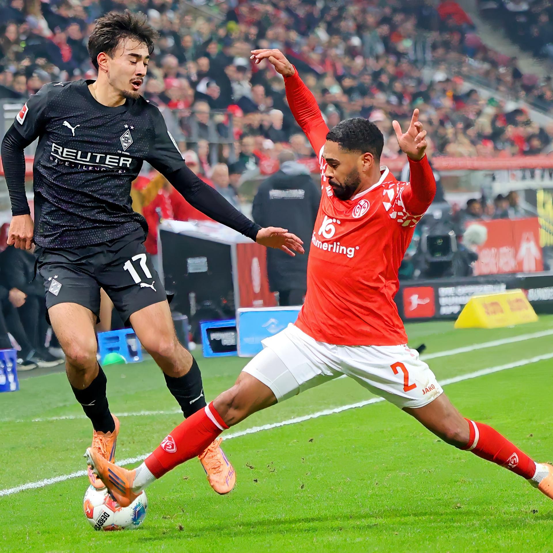 Das Bild zeigt einen Zweikampf zwischen Jens Castrop von Borussia Monchengladbach und Phillipp Mwene vom FSV Mainz 05 beim Spiel der beiden Clubs am 5. Dezember 2025.