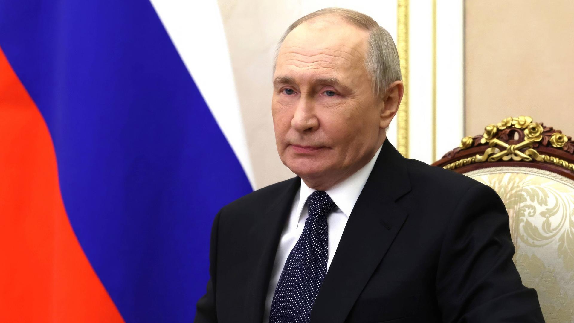 Der russische Präsident Wladimir Putin sitzt an einem Schreibtisch vor einer Russland-Flagge